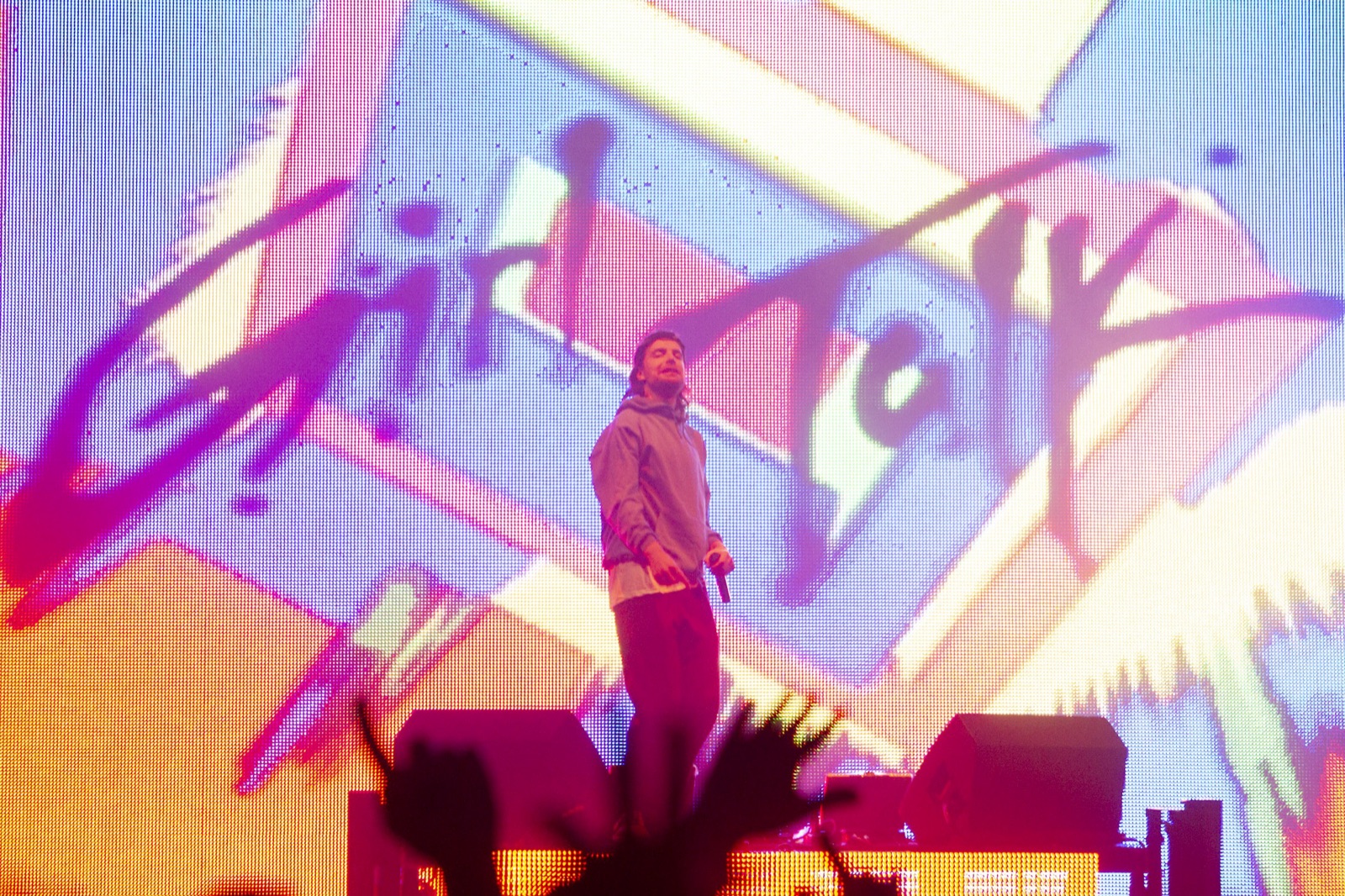 Girl Talk stands with a microphone in front of a pink and purple Girl Talk logo on the video wall.